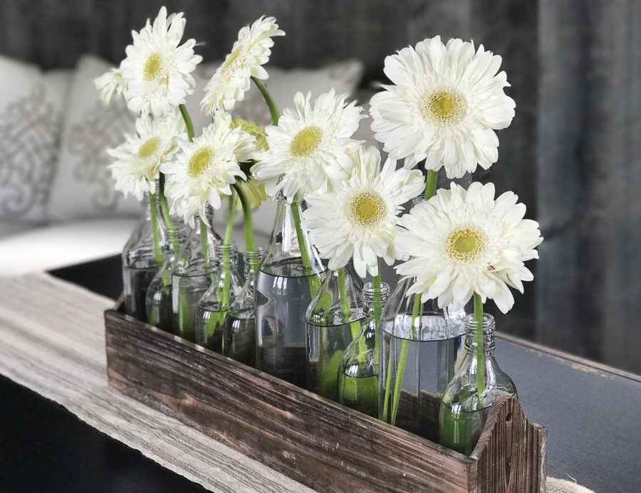 Daisies in glass jars in a wooden crate