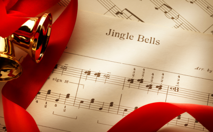 Bells with a red ribbon laying on jingle bells sheet music