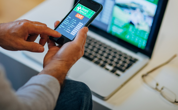 man on his phone with a laptop in the background